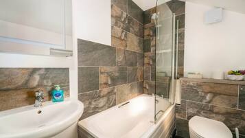 A bathroom with a bathtub, toilet, and sink.