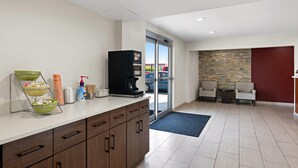 A modern kitchen with a coffee machine, a fruit bowl, and a coffee dispenser. - Quality Suites Wildwood - The Villages (Wildwood)