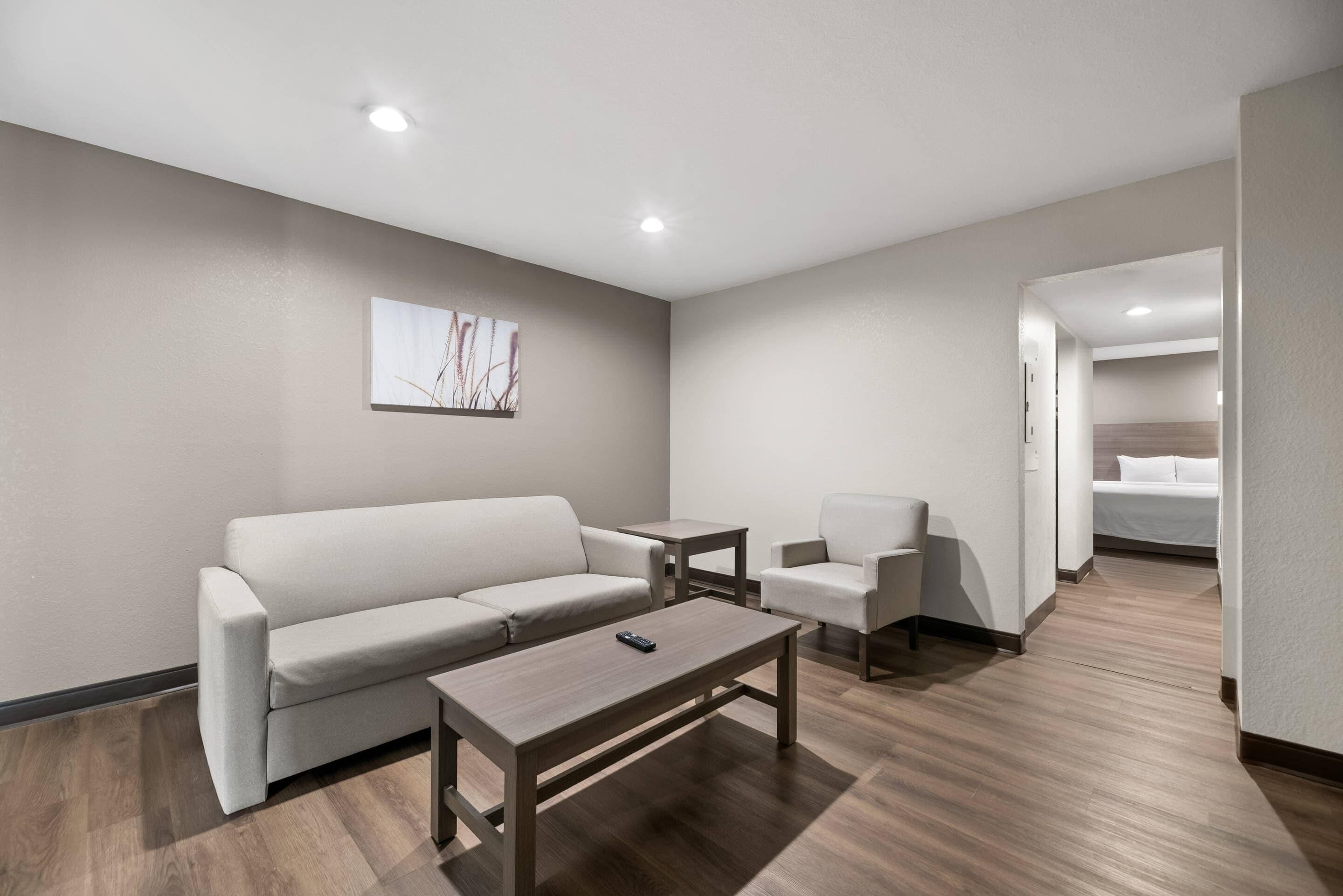 Habitació d'hotel moderna amb sofà, butaca, taula petita i un llit.