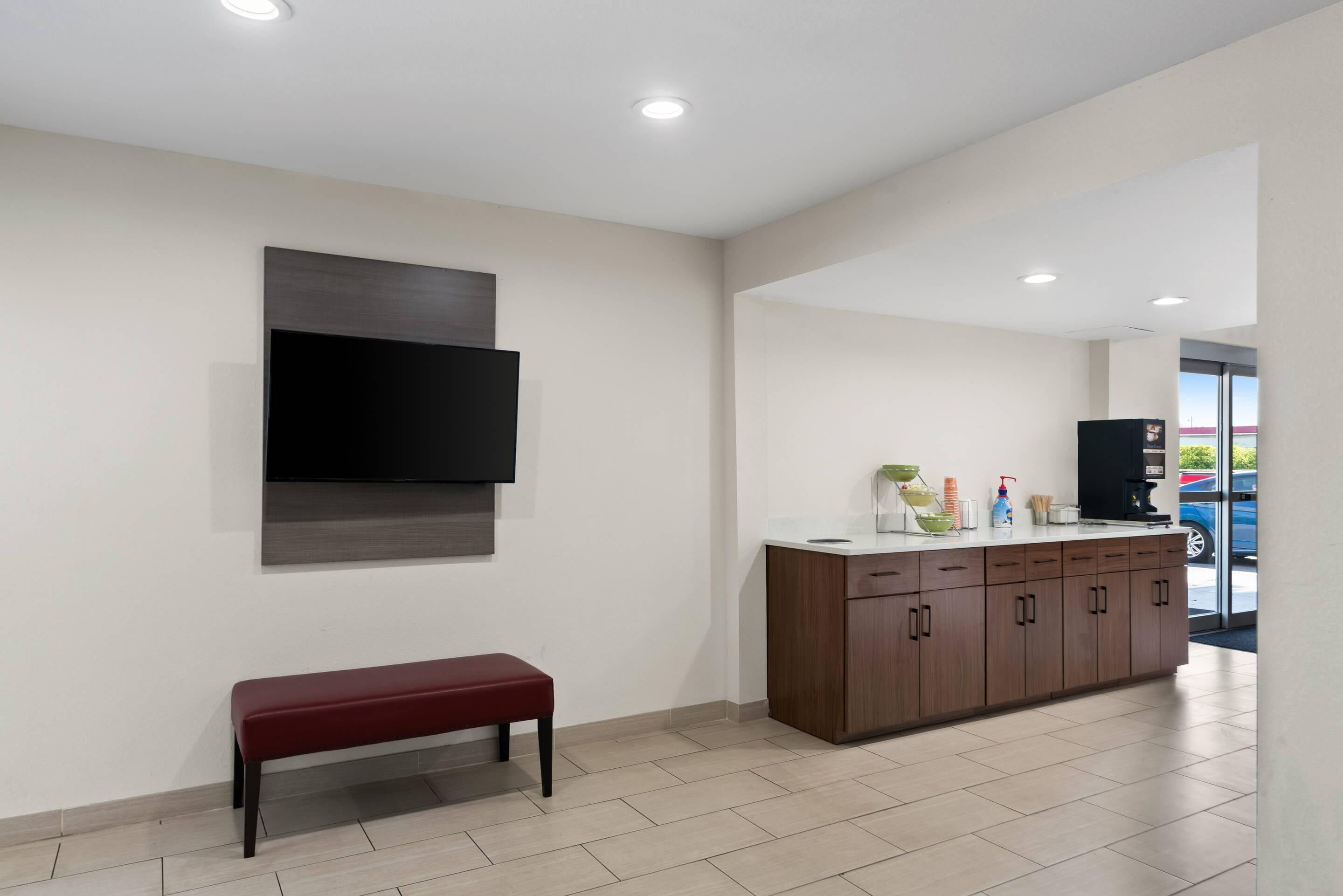 A modern kitchen with a flat-screen TV, a wooden cabinet, and a bench.