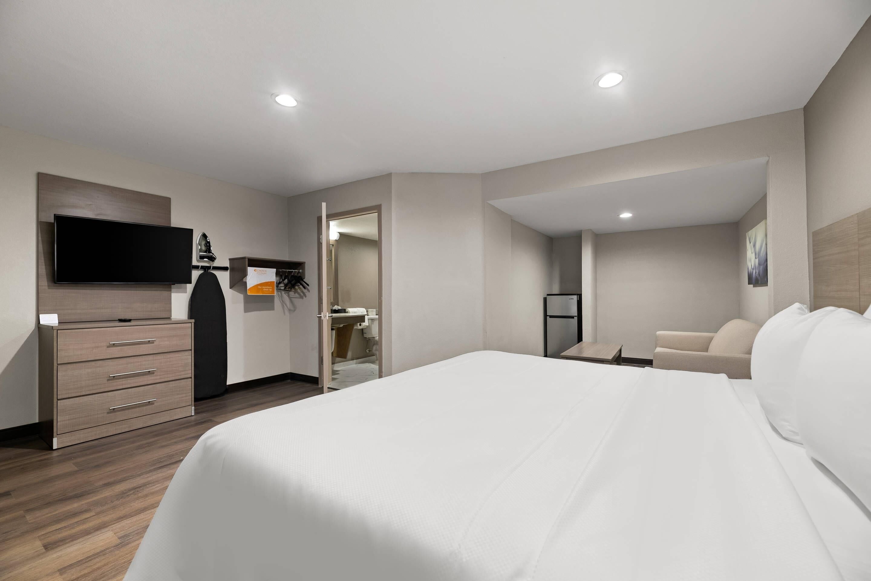 Ein Hotelzimmer mit Bett, Fernseher, Kleiderschrank, Schreibtisch und Badezimmer.