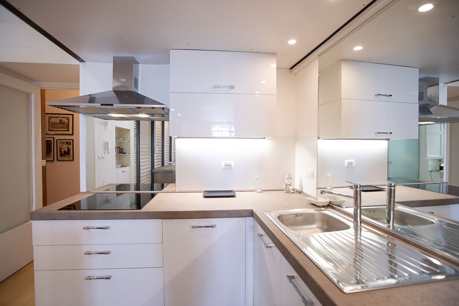 A modern kitchen with white cabinetry, stainless steel appliances, and a large island with a sink.