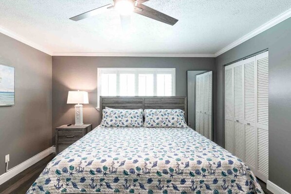 A bedroom with a bed, nightstand, lamp, window, and closet.