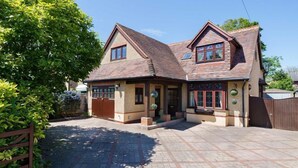 Une maison à deux étages avec une façade en briques, une allée pavée et un portail en bois.