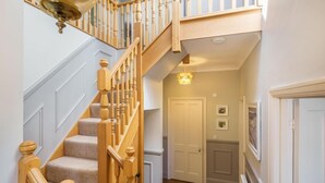 Un escalier avec des balustrades en bois et un luminaire au-dessus de la porte.