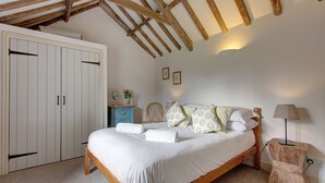 Een slaapkamer met een houten bed, een witte kast en een nachtkastje met een lamp.