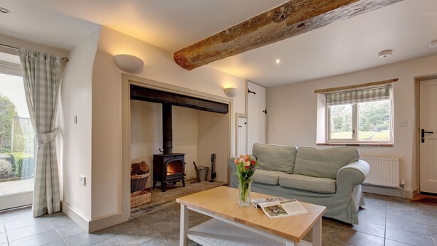 A living room with a sofa, a wooden coffee table, a fireplace, and a window with curtains.