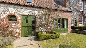 A stone house with a green door, a small window, and a brick wall. - Riding Stable - sleeps 6 guests  in 3 bedrooms (Holt)