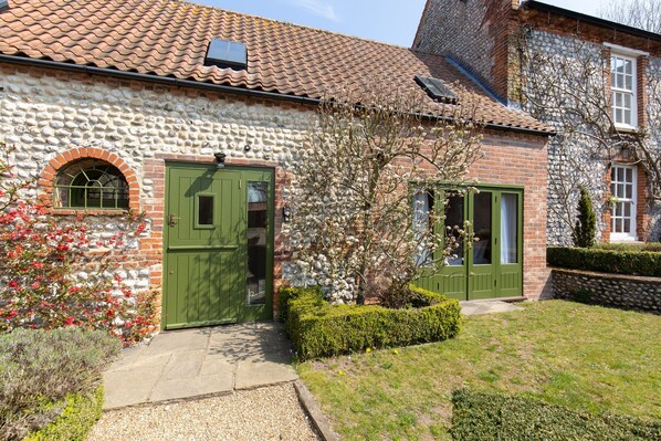 A stone house with a green door, a small window, and a brick wall. - Riding Stable - sleeps 6 guests in 3 bedrooms (Holt)
