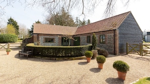 A traditional stone building with a tiled roof, a gravel driveway, and a wooden gate. - Wash House - sleeps 6 guests  in 3 bedrooms (Holt)