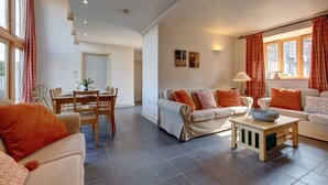 A spacious living room with a dining area, large windows with curtains, and a modern interior design. - Workshop - sleeps 8 guests  in 4 bedrooms (Holt)