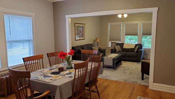 A dining area with a table set for six, a living room with a sofa and a coffee table, and a hallway leading to another room. - Updated Forest Park 3 BR Bungalow (Forest Park)