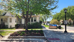 A residential street with a two-story house, a sidewalk, a bench, and a 'ONE WAY' sign. - Updated Forest Park 3 BR Bungalow (Forest Park)