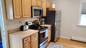 A modern kitchen with wooden cabinets, a stainless steel refrigerator, a built-in oven, a microwave, a coffee maker, and a toaster. - Updated Forest Park 3 BR Bungalow (Forest Park)
