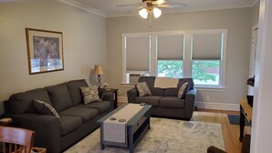 A living room with two sofas, a coffee table, and a ceiling fan. - Updated Forest Park 3 BR Bungalow (Forest Park)