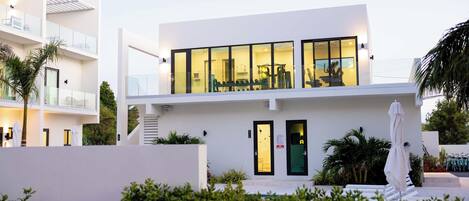 Un edificio moderno de dos pisos con amplios ventanales de vidrio, una escalera y un área de piscina.