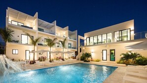 A modern hotel with a swimming pool, outdoor seating, and a waterfall feature. - Seascape Grace Bay Hotel & Townhome Villas (Providenciales)