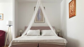 Ein Bett mit Baldachin, zwei Nachttische, eine Stehlampe und Kunstwerke an den Wänden.
