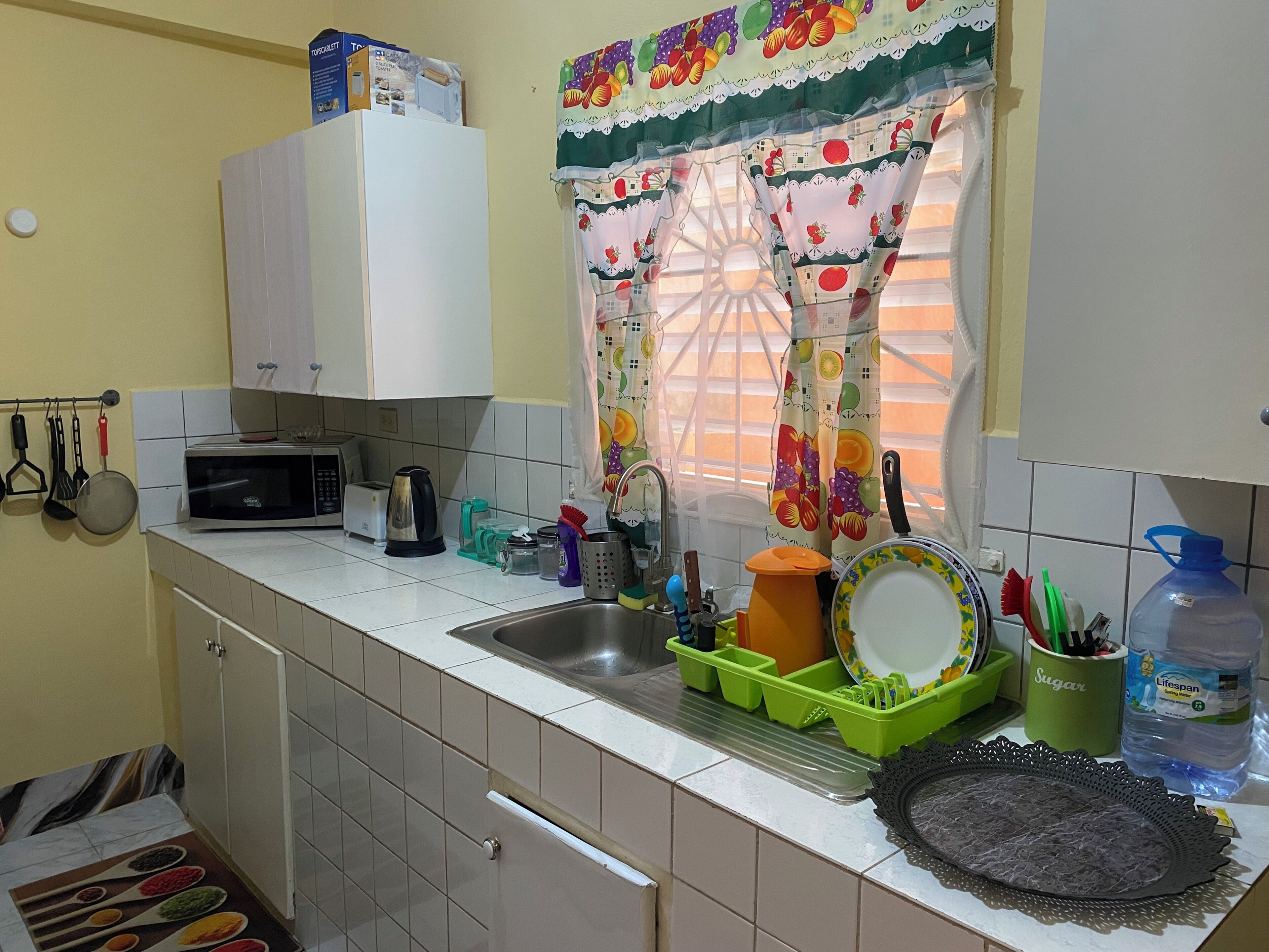 A kitchen with a microwave, toaster, sink, and various utensils.
