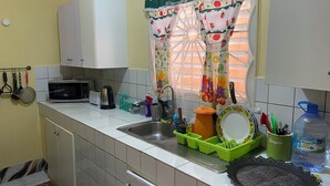 A kitchen with a microwave, toaster, sink, and various utensils. -  Rockery Villa is a cozy 1 Bedroom Townhouse an ideal space for a  getaway. (Port Antonio)