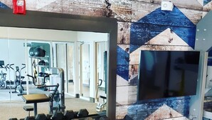Une salle de sport équipée de matériel d’exercice, notamment des haltères et un miroir qui reflète l’intérieur.