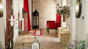 An interior with a stone wall, red chair, and a red curtain. - Suites La Posada de Pilar (Córdoba)