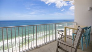 A balcony with a view of the ocean, a table, and two chairs. - Beachfront Family Condo. Luxury Resort. Sleeps 4-6 (Panama City Beach)