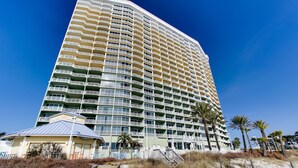 A high-rise hotel with multiple balconies, a beachside location, and a wooden boardwalk. - Beachfront Family Condo. Luxury Resort. Sleeps 4-6 (Panama City Beach)