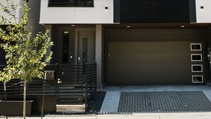 A modern two-story building with a garage, a balcony, and a small tree in the foreground. - Buffalo Heights (Houston)