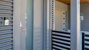 A modern entrance with a grey door, a metal gate, and a wooden ceiling. - Buffalo Heights (Houston)