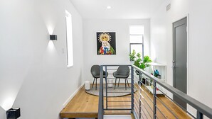 A modern staircase with wooden steps and metal railings, leading to a dining area with a table and chairs. - Buffalo Heights (Houston)