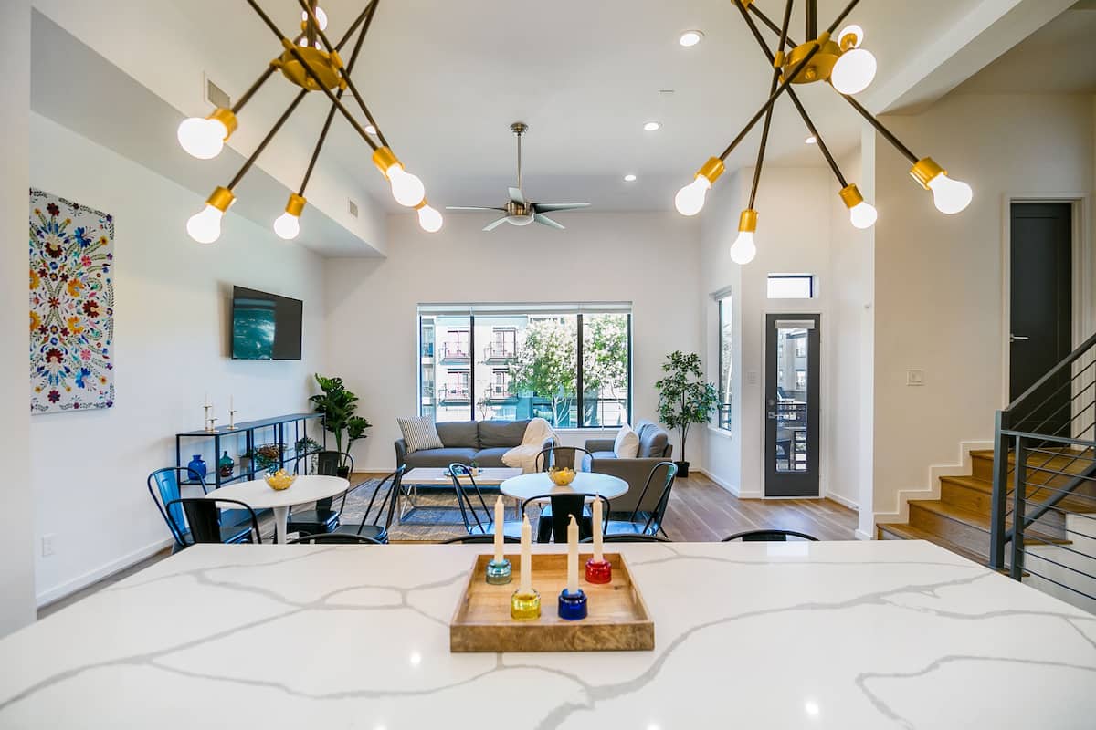 A modern living room with a marble dining table, a ceiling fan, and a staircase.