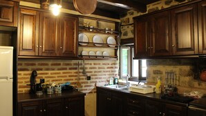 Une cuisine avec des meubles de rangement en bois, un mur en briques et un porte-ustensiles suspendu.