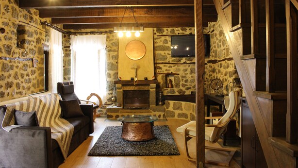 Un intérieur rustique avec une cheminée en pierre, des meubles en bois et un coin salon confortable.