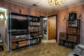 Ein Zimmer mit einem großen Flachbildfernseher, Bücherregalen und einem Spiegel an der Wand.
