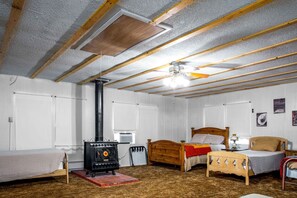 Une pièce comprenant un lit, une chaise en bois, une petite table, un radiateur et un ventilateur de plafond.