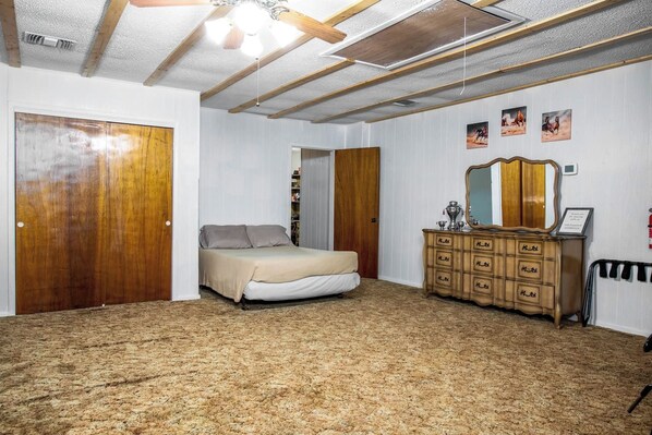 A bedroom with a bed, wooden wardrobe, and a ceiling fan.