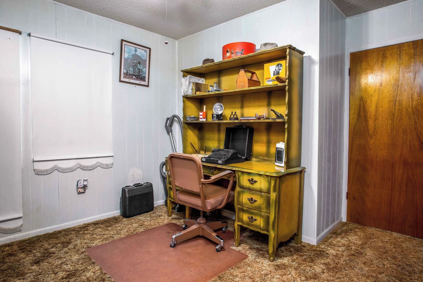 A room with a desk, chair, and a door.