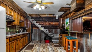Une cuisine rustique avec des meubles en bois, un escalier et un ventilateur de plafond.
