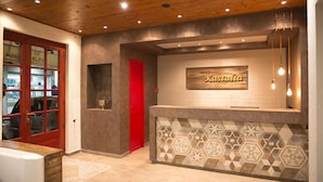 A reception area with a wooden ceiling, a red door, and a wall-mounted sign that reads "Kastalia". - Kastalia Hotel (Delphi)