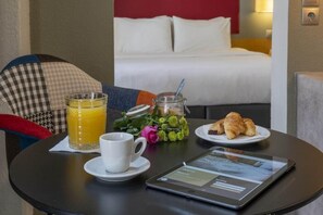 A breakfast setup with a tablet, a cup of coffee, a glass of orange juice, and croissants on a table. - Kastalia Hotel (Delphi)