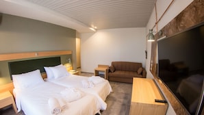 A hotel room with two beds, a sofa, a TV, and a desk. - Kastalia Hotel (Delphi)