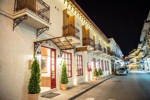 A row of white buildings with balconies and wooden shutters, a sign for 'Kastalia Hotel', and a street with parked cars. - Kastalia Hotel (Delphi)