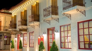 A hotel with multiple balconies, red-framed windows, and potted plants. - Kastalia Hotel (Delphi)