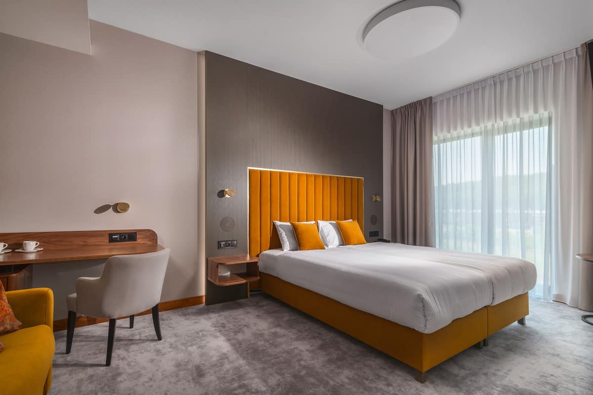 A modern hotel room with a large bed, a desk, and a chair.