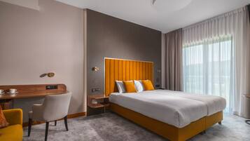 Una habitación de hotel moderna con una cama grande, un escritorio y una silla.