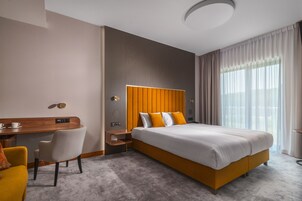 Una habitación de hotel moderna con una cama grande, un escritorio y una silla.
