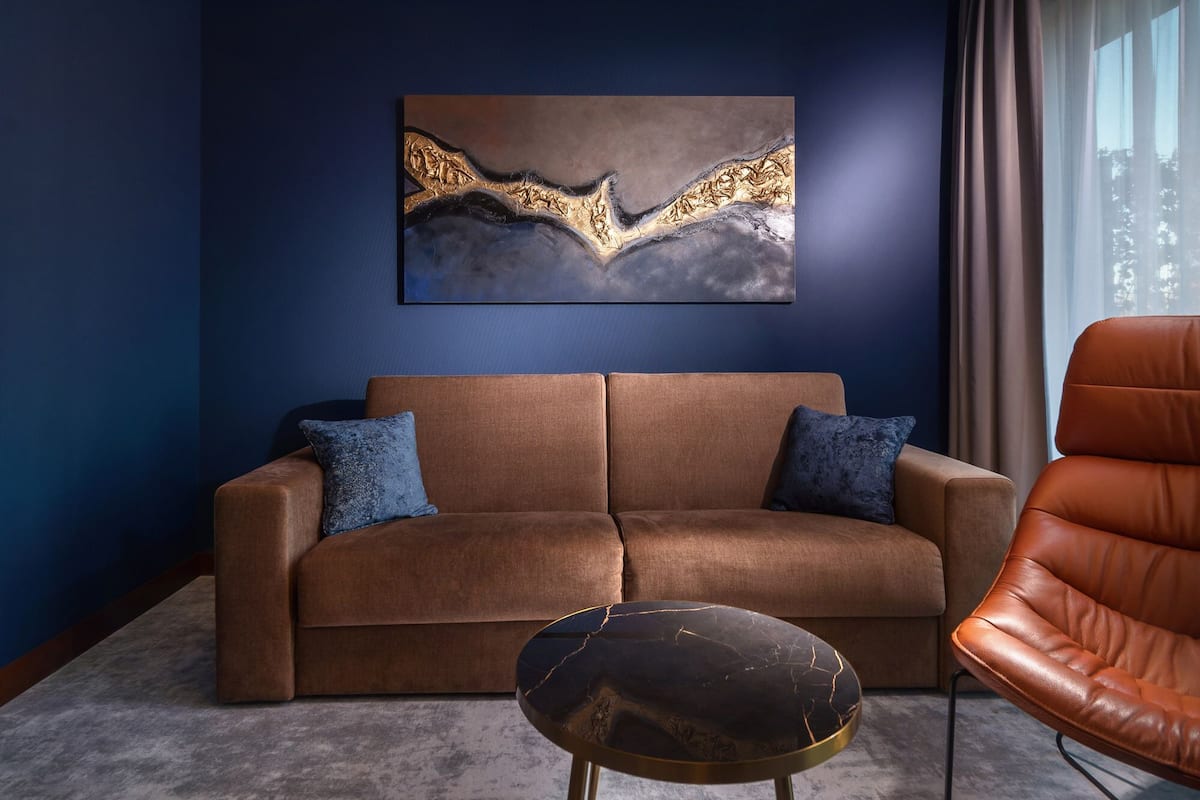 A living room with a brown sofa, two blue cushions, a black coffee table, and a brown leather chair.