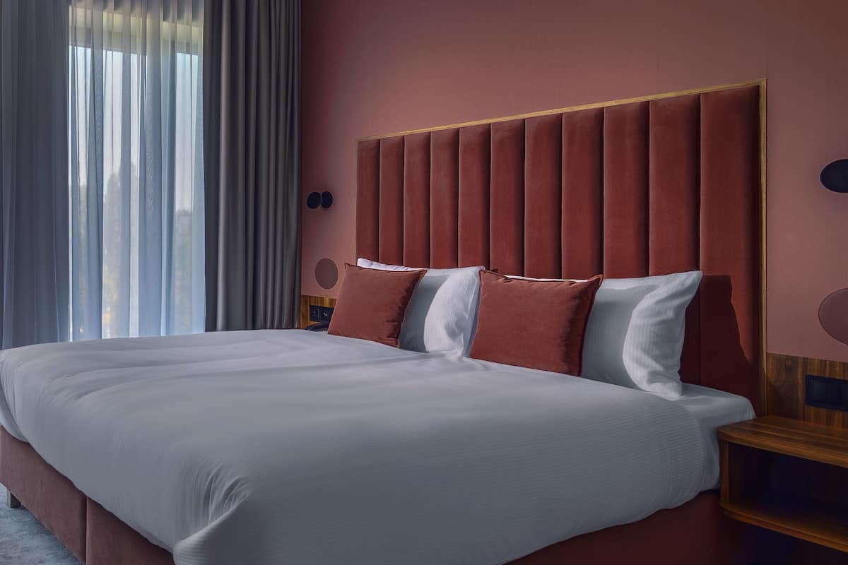 A large bed with a headboard, a bedside table, and a nightstand.
