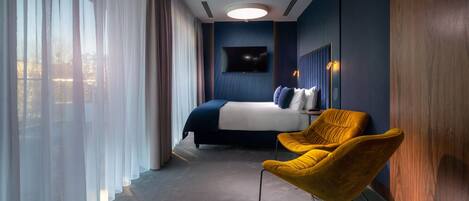Ein modernes Hotelzimmer mit einem großen Bett, einem Fernseher und einem gelben Sessel.